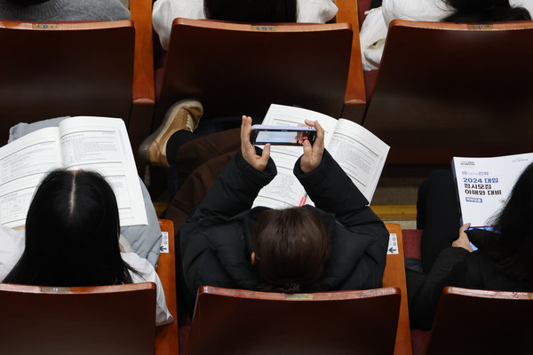 지난 달 11일 오후 서울 동작구 숭실대학교 한경직기념관에서 열린 서울시교육청 주최 2024 대입 정시모집 설명회에서 한 수험생 학부모가 지원전략 설명을 들으며 스마트폰을 이용해 강의자료를 기록하고 있다. 엲합뉴스