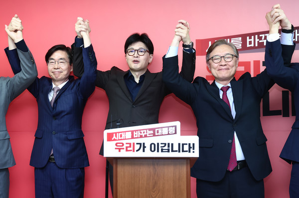 국민의힘 한동훈 대선 경선 후보가 18일 서울 여의도 선거 사무소에서 열린 캠프 인선 등 현안 관련 기자회견에서 최재형(오른쪽), 조경태 공동선대위원장과 손을 맞잡고 기념촬영을 하고 있다. 연합뉴스