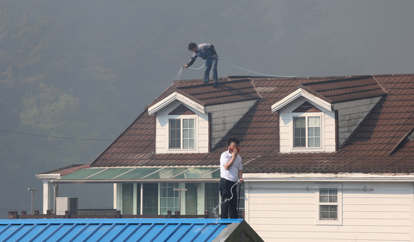 28일 오후 2시 1분께 대구 북구 노곡동 함지산에서 산불이 발생한 가운데 주민들이 주택 지붕에 물을 뿌리고 있다. 연합뉴스