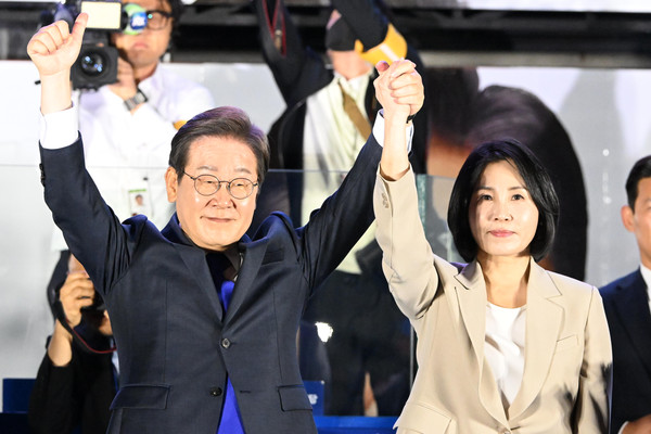 제21대 대통령 당선이 확실시되는 더불어민주당 이재명 대선 후보와 부인 김혜경 여사가 4일 서울 여의도 국회 인근에서 당 주최로 열린 국민개표방송 행사에 참석해 시민들을 향해 두 팔을 들어올려 인사하고 있다. 연합뉴스