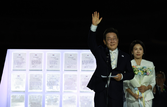 이재명 대통령과 김혜경 여사가 15일 서울 세종대로 광화문광장에서 열린 제21대 대통령 국민임명식 '광복 80년, 국민주권으로 미래를 세우다' 행사에서 국민 대표 80인으로부터 '빛의 임명장'을 받은 뒤 감사 인사를 하고 있다. 연합뉴스