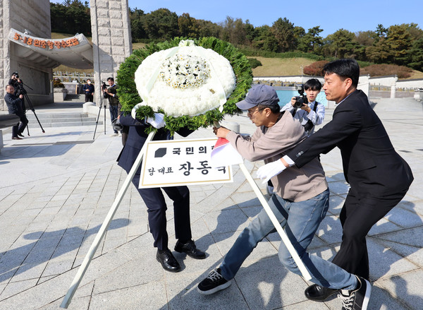 6일 오후 광주 북구 국립5·18민주묘지에서 국민의힘 장동혁 대표의 참배 화환을 시민단체 관계자가 이동시키고 있다. 연합뉴스